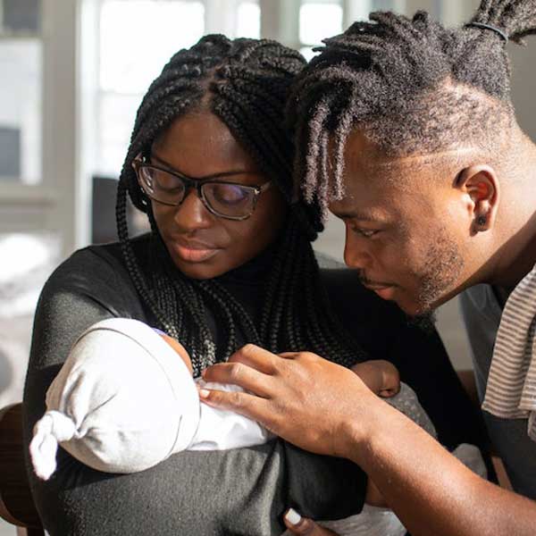 Young black couple cuddling newborn