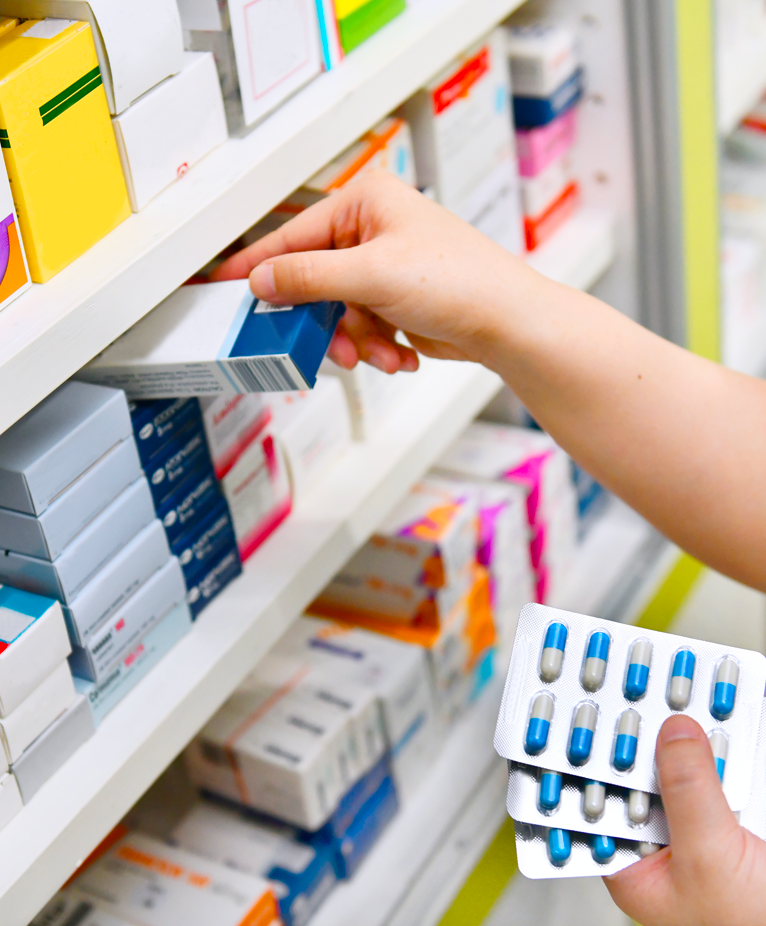 Close up of prescription drugs on shelf in pharmacy being restocked by clinician