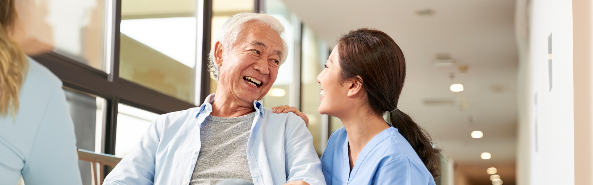 Senior asian man sitting in health center being greeted by medical provider